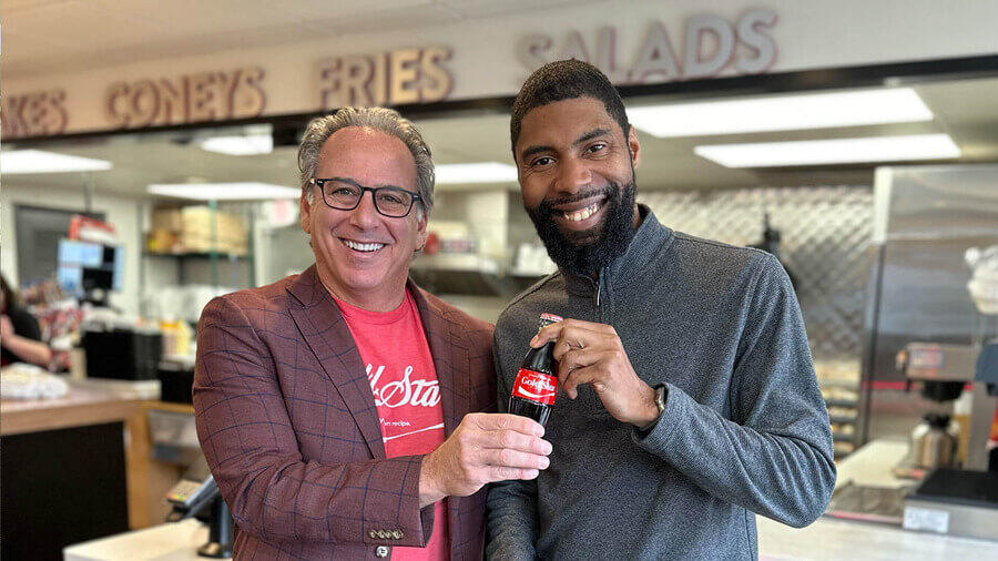 Two men holding a bottle of coke