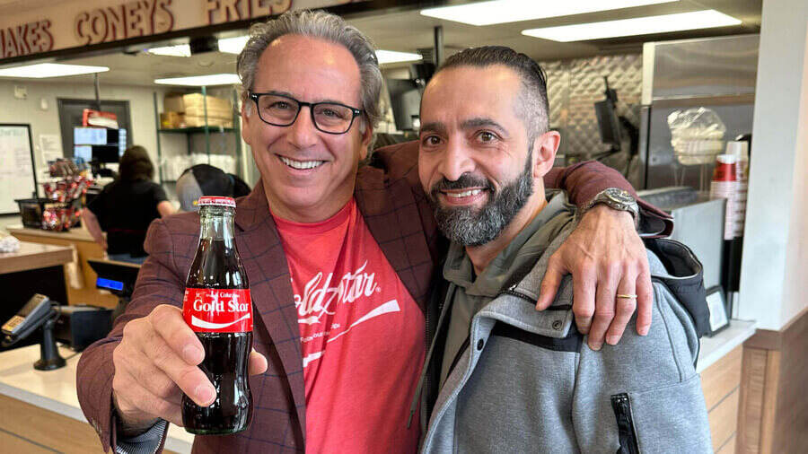 Two men holding a bottle of coke