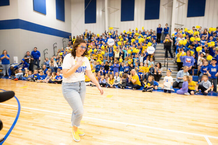 Teacher walking into a gym full of students